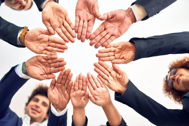 Grupo de empresários sorrindo feliz e confiante. Em pé em um círculo com sorriso no rosto fazendo símbolo com as mãos juntas no escritório
. - Foto, Imagem