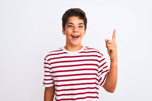Hezký teenager chlapec stojící nad bílým izolovaným pozadím ukazující prstem nahoru s úspěšným nápadem. Utekl a byl šťastný. Číslo jedna. - Fotografie, Obrázek