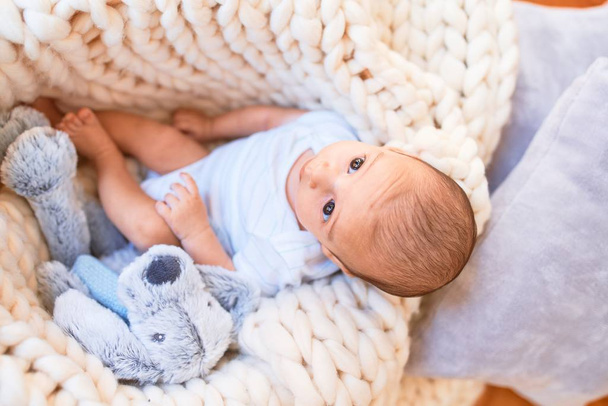 Imádnivaló baba fekszik a takaró felett otthon a földön. Újszülött pihentető és pihentető kényelmes játékmackó - Fotó, kép