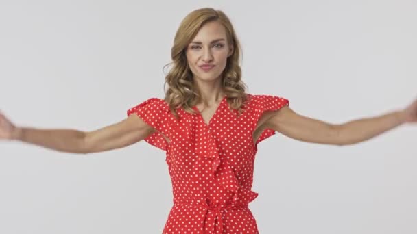 Displeased pretty blonde woman in dress standing with arms on hips and showing thumb down gestures after that over grey background - Materiał filmowy, wideo