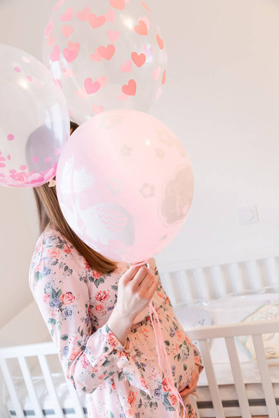 Young pregnant woman is holding pink balloons - Gender Reveal -  - Photo, Image