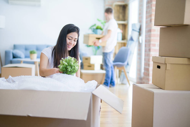 Young beautiful couple sitting on the floor at new home around cardboard boxes celebrating surprised and amazed for success with arms raised and open eyes. Winner concept. - Photo, Image