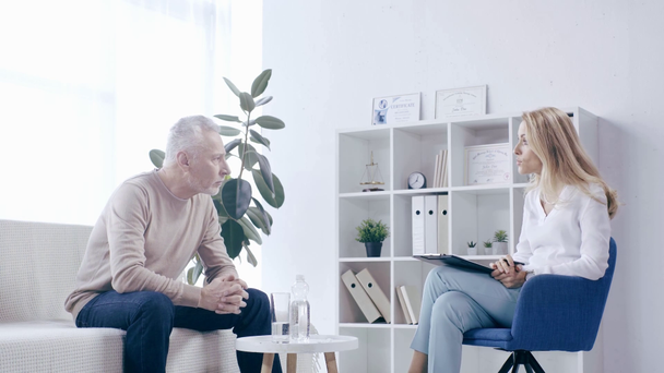 pozorný psycholog naslouchá zralému muži sedícímu na gauči - Záběry, video