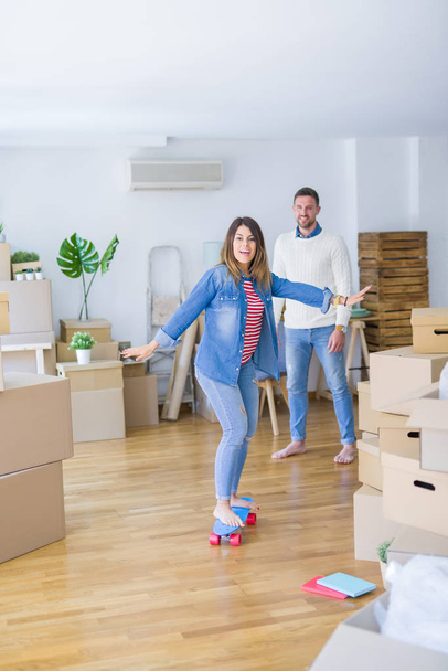 Young beautiful couple at new home around cardboard boxes - Photo, Image