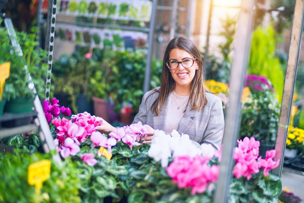 Young beautiful woman smiling happy and confident. Standing with smile on face at florist - Fotoğraf, Görsel