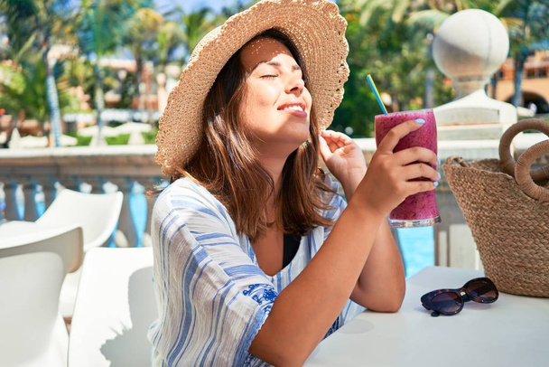 Krásná žena sedí u bazénu v hotelu resort pití zdravé smoothie enyojing letní dovolená - Fotografie, Obrázek
