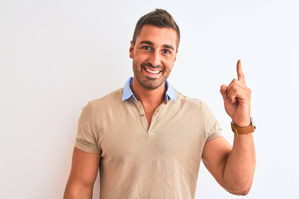 Young handsome man wearing elegant t-shirt over isolated background pointing finger up with successful idea. Exited and happy. Number one. - Photo, Image