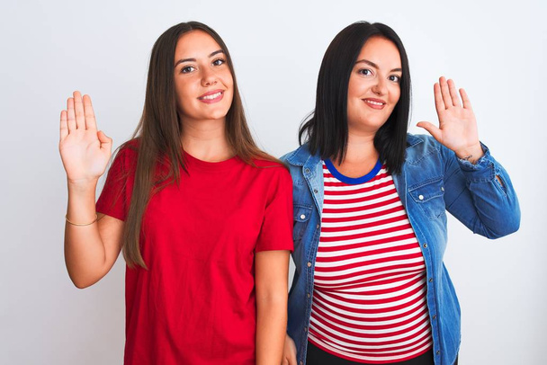Young beautiful women wearing casual clothes standing over isolated white background Waiving saying hello happy and smiling, friendly welcome gesture - Photo, Image