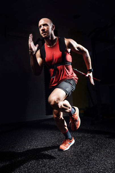 Muscular man during workout with suspension straps TRX on dark studio. - Photo, Image