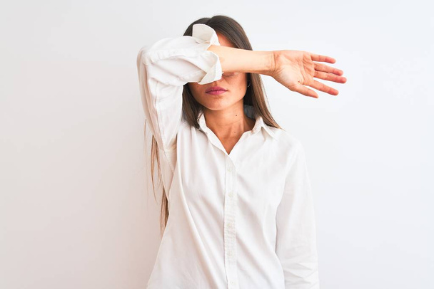 Young beautiful businesswoman wearing glasses standing over isolated white background covering eyes with arm, looking serious and sad. Sightless, hiding and rejection concept - Photo, image