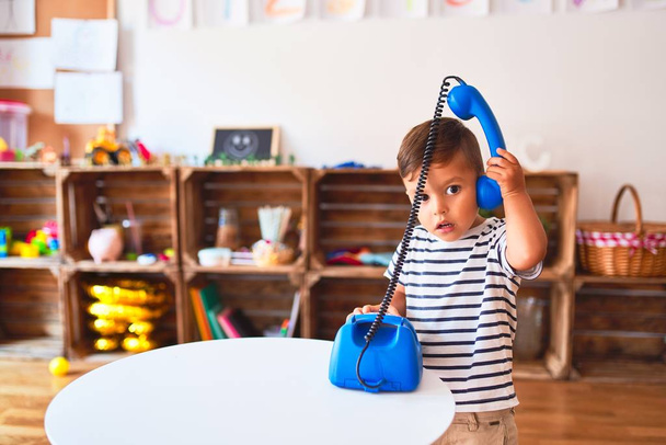 Красивый мальчик играет с винтажным синим телефоном в детском саду
 - Фото, изображение