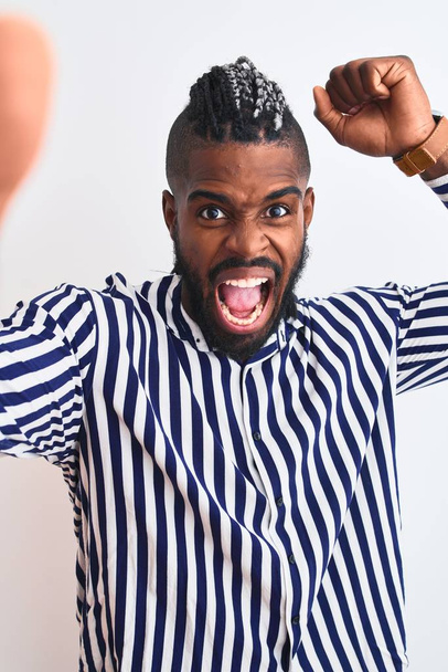 afrikanisch-amerikanischer Mann mit Zöpfen macht Selfie mit der Kamera vor isoliertem weißen Hintergrund genervt und frustriert schreit vor Wut, verrückt und schreit mit erhobener Hand, Wut Konzept - Foto, Bild