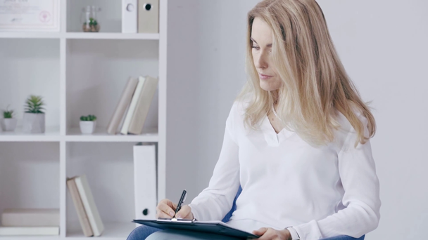 attentive psychologists listen to patient and writing on clipboard - Footage, Video
