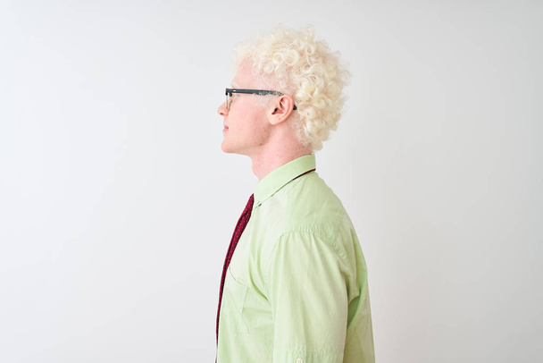 Fiatal albínó üzletember visel ing és nyakkendő áll elszigetelt fehér háttér keres oldalra, pihenjen profil pózol természetes arc magabiztos mosollyal. - Fotó, kép