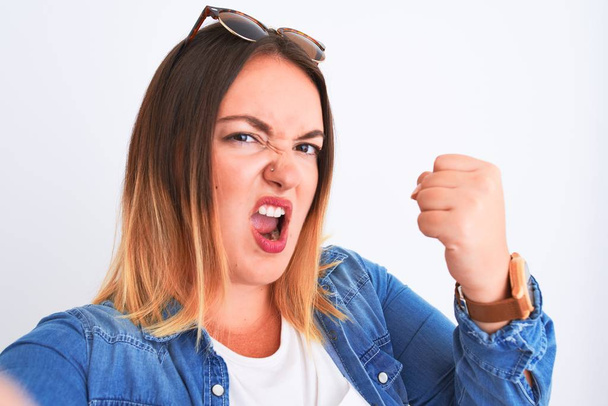 Young beautiful woman wearing denim shirt  standing over isolated white background annoyed and frustrated shouting with anger, crazy and yelling with raised hand, anger concept - Φωτογραφία, εικόνα