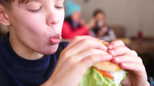 Ребенок ест булочку с котлетой и сыром в ресторане быстрого питания
 - Кадры, видео