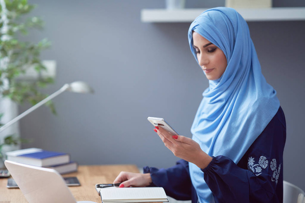 Muszlim felnőtt nő okostelefont használ - Fotó, kép