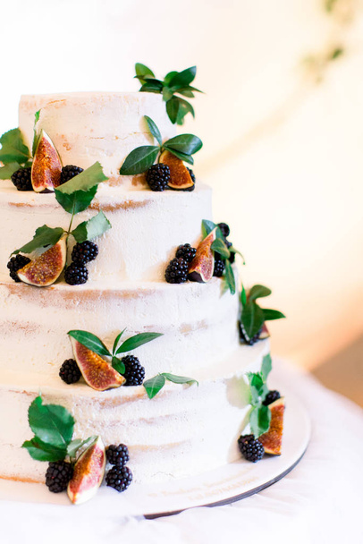 Delicious cake with figs and berries. Rustic wedding cake with fresh berries and figs served on table - Fotoğraf, Görsel