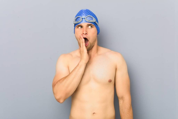 Jonge professionele zwemmer zegt een geheim hot braking nieuws en kijkt opzij - Foto, afbeelding