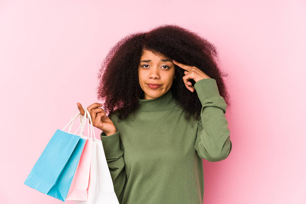 Young afro woman shopping isolated Young afro woman buying isolaYoung afro woman holding a roses isolated having an idea, inspiration concept - Φωτογραφία, εικόνα