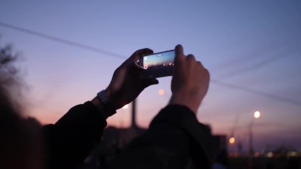 Heren handen met horloges nemen foto 's van de zonsondergang van de nacht stad - Video