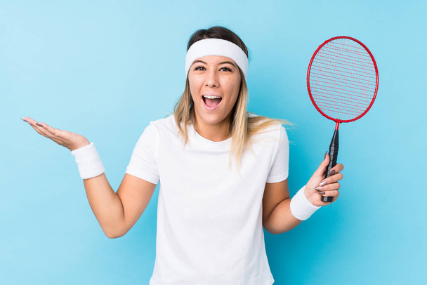Badminton oynayan beyaz bir kadın yalnız başına hoş bir sürprizle karşılaşıyor, heyecanlı ve el kaldırıyor.. - Fotoğraf, Görsel