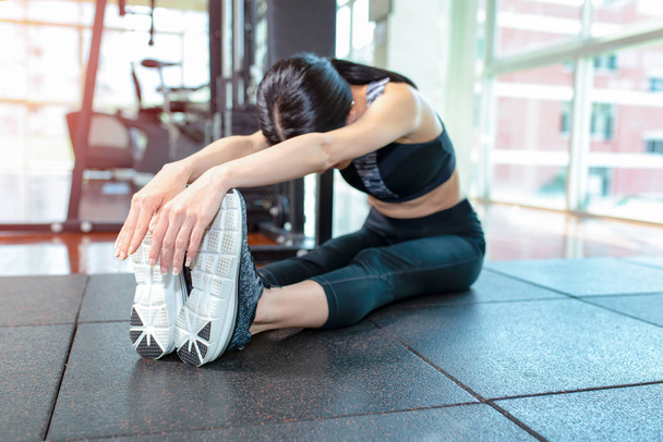 Mujer en forma estirando su pierna para calentarse en el gimnasio
 - Foto, imagen