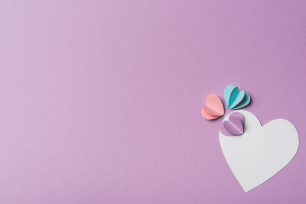 top view of blank card with colorful paper hearts on violet background - Fotoğraf, Görsel