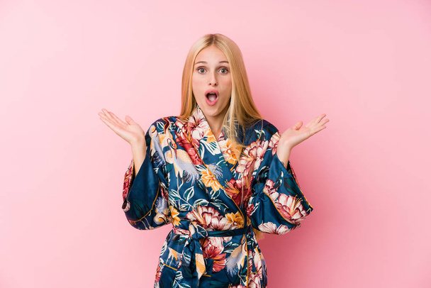 junge blonde Frau im Kimono-Pyjama überrascht und schockiert. - Foto, Bild
