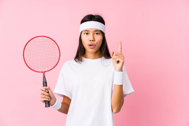 Jovem chinesa jogando badminton em um fundo rosa tendo alguma grande ideia, conceito de criatividade
. - Foto, Imagem
