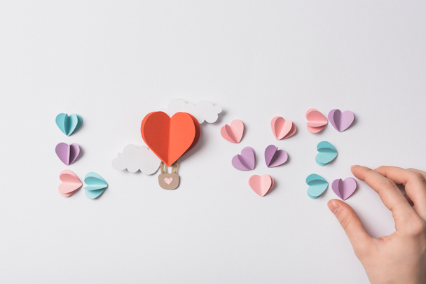 top view of love lettering made of colorful paper hearts and air balloon with clouds on white background - Photo, Image