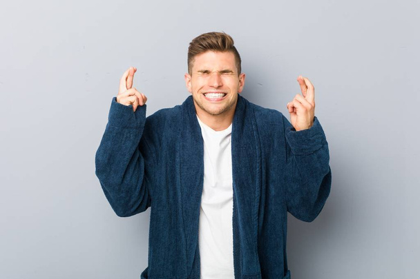 Jeune homme caucasien portant un pyjama croisant les doigts pour avoir de la chance
 - Photo, image