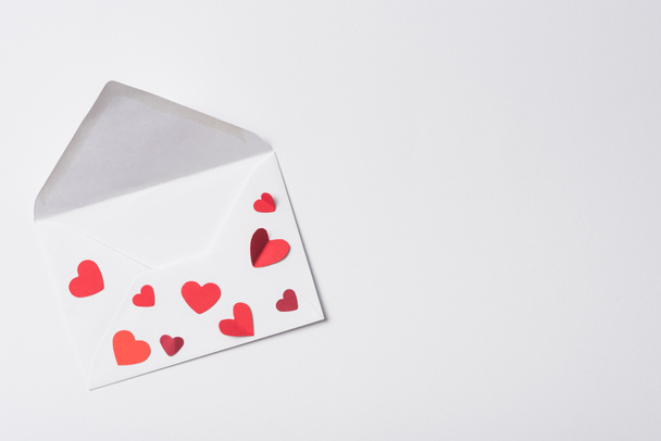 vrchní pohled na obálku Valentines s červenými srdíčky na bílém pozadí - Fotografie, Obrázek