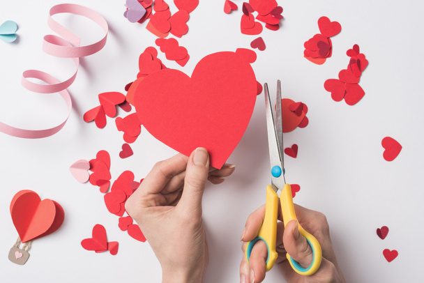 cropped view of woman holding red heart and scissors on white background - Photo, Image