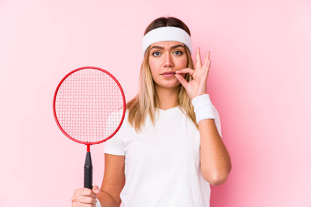 jonge vrouw spelen badminton geïsoleerd met vingers op lippen houden van een geheim. - Foto, afbeelding