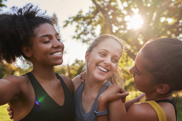 Parkta güneşli bir günde gülümseyen ve eğlenen bir grup farklı bayan arkadaş. Güneşli bir günde birbirleriyle gülen spor arkadaşları.  - Fotoğraf, Görsel