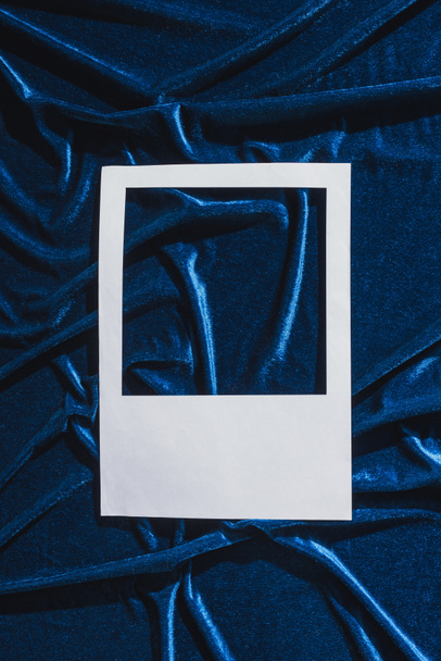 top view of empty white photo frame on blue velour cloth - Foto, Imagem