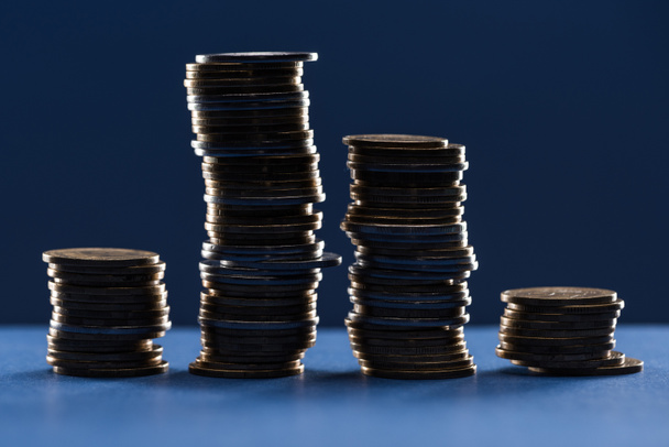 Mavi arkaplanda gölgeli metal para yığınları - Fotoğraf, Görsel