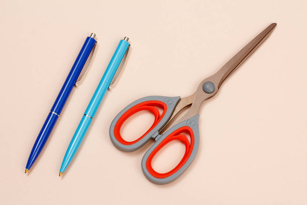 Two pens and scissors on a beige background. - Fotografie, Obrázek