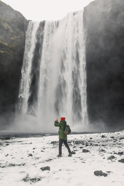 young handsome man standing near waterfall on Iceland mountains background - Foto, Imagen