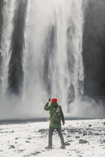 young handsome man standing near waterfall on Iceland mountains background - Фото, зображення