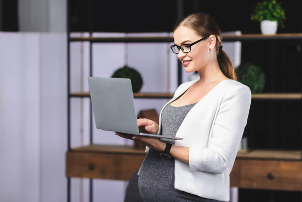 Веселая беременная женщина работает в офисе
 - Фото, изображение