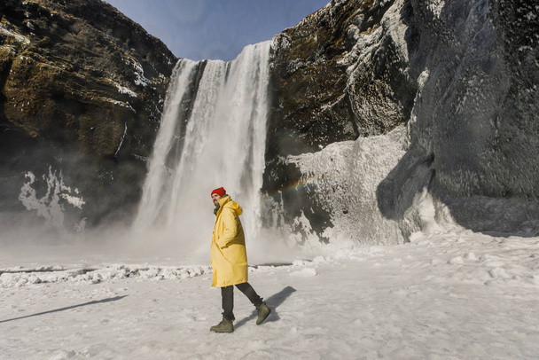 young handsome man standing near waterfall in Iceland mountains background  - Foto, Imagen