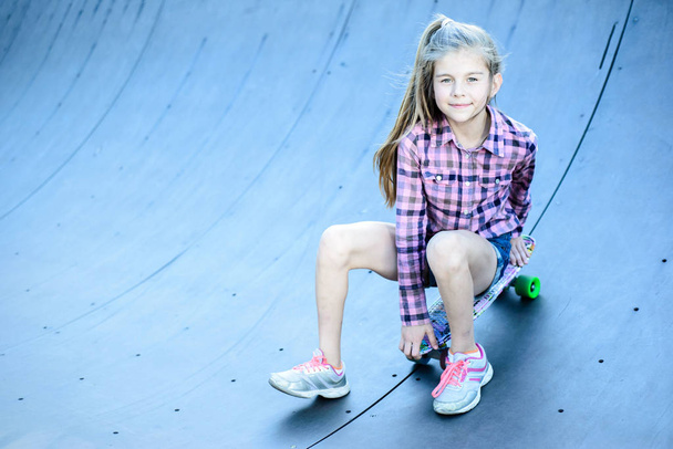 little girl sitting on a skateboard, skatepark on the street - Photo, Image
