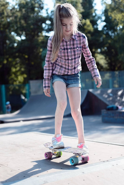 Skater paseos femeninos en monopatín en la rampa del parque de skate. Mujer joven practicando skate al aire libre en skate park
. - Foto, Imagen