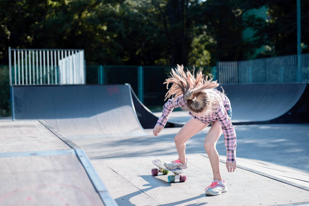 tiener meisje het uitvoeren van een truc met een skateboard op het sportveld - Foto, afbeelding