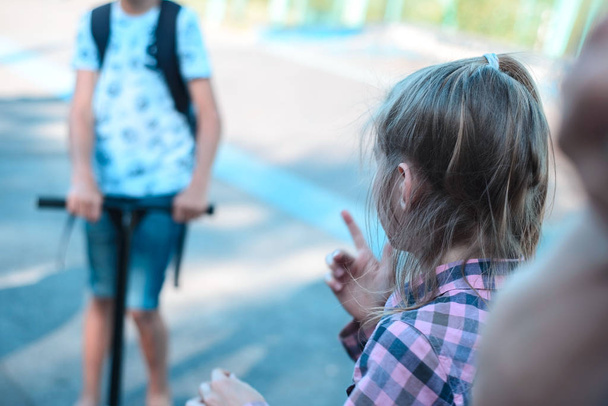 nastolatka dziewczyna wskazując palcem na chłopca jazda na skuterze - Zdjęcie, obraz