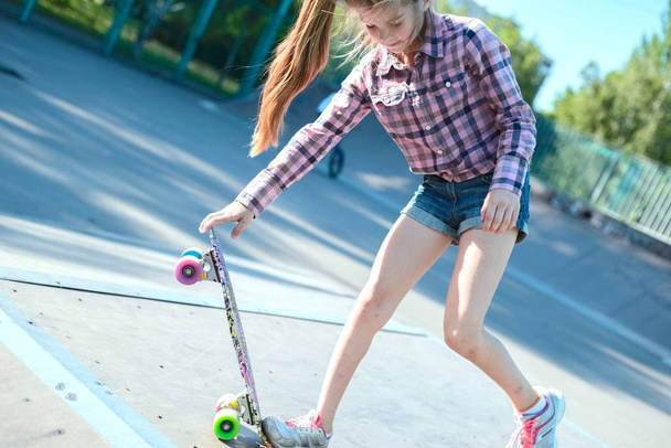 Маленькая девочка-подросток, проделывающая трюк со скейтбордом, находясь в скейтпарке
 - Фото, изображение