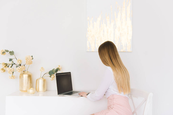 Portrait of a beautiful young businesswoman in a skirt and blouse with a laptop on a white background in a modern interior - Foto, imagen