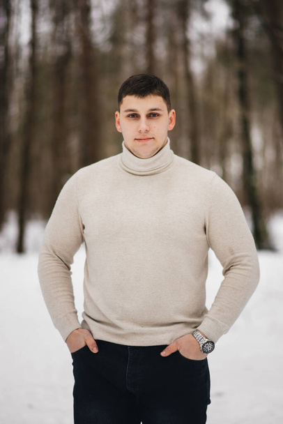 Portrait of a stylish young man on the background of a snowy forest - Photo, image
